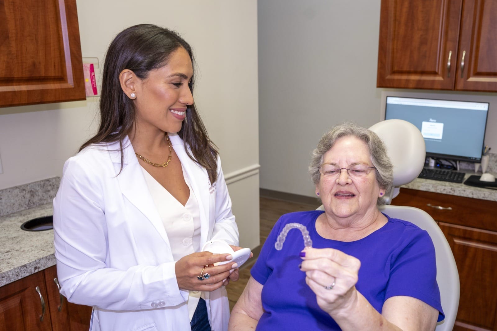 A patient observing an Invisalign aligner while Dr. Rodriguez looks on