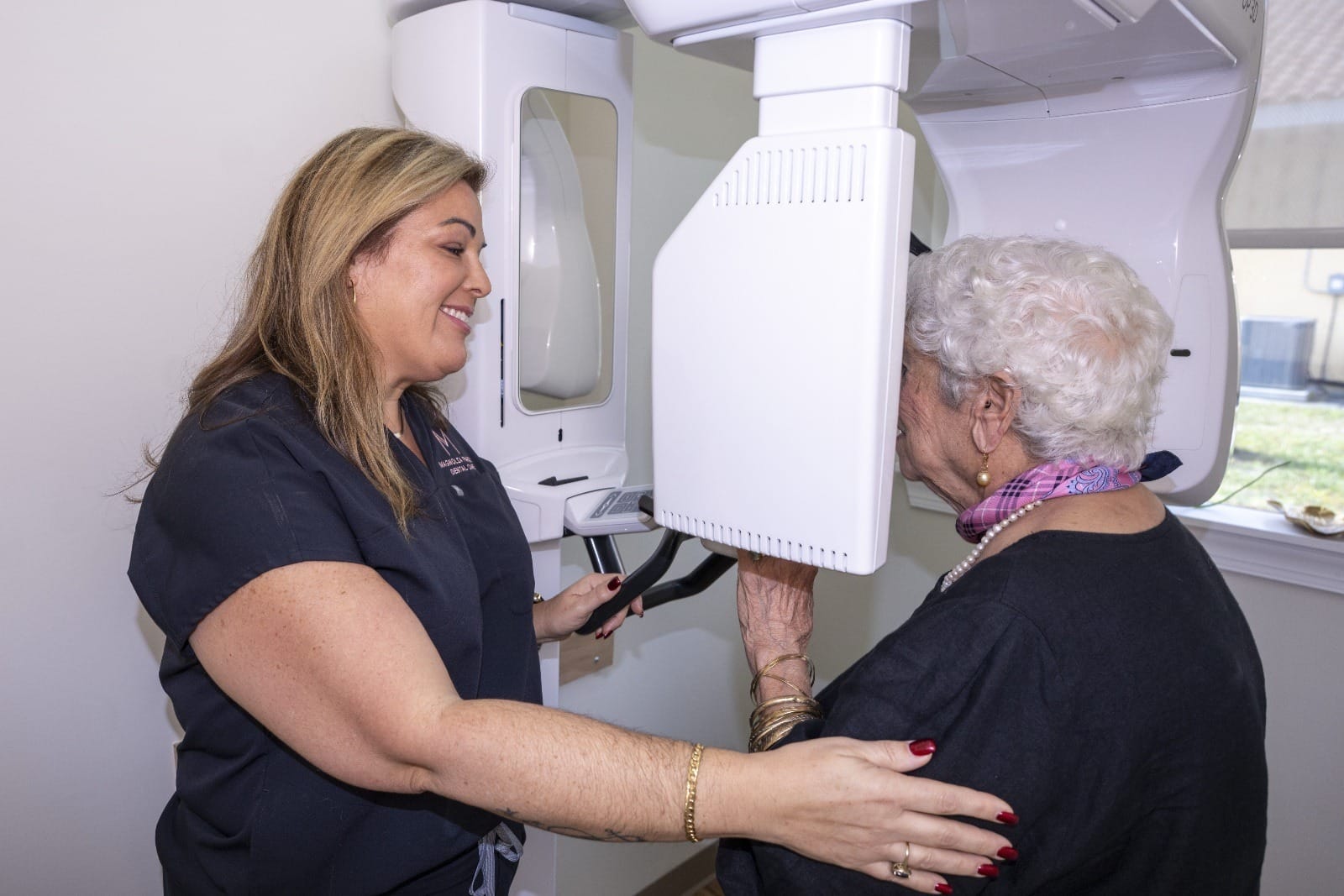 A dental assistant assists a patient into a 3D scanner