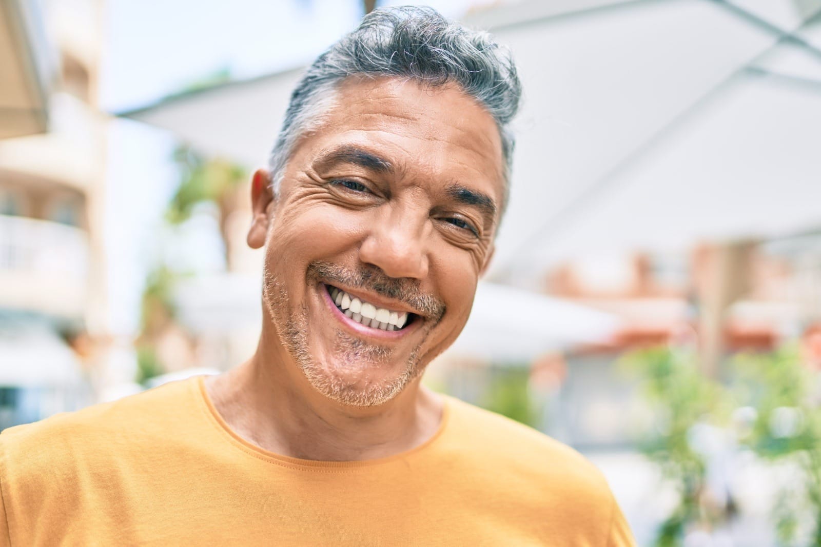 Middle age grey-haired man smiling happy walking at street of city.